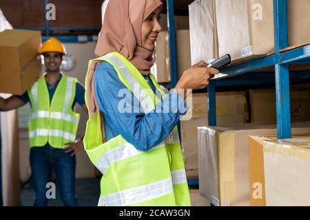 Asiatische Islam muslimische weibliche Lagerarbeiter Inventar mit Barcode-Scanner mit indischen Arbeiter halten Karton im Lager Verteilung. Für Busi Stockfoto