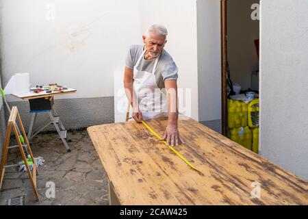 Professioneller Zimmermann baut einen Holztisch im Freien Werkstatt Stockfoto