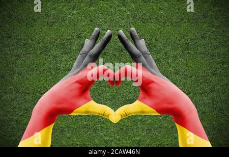 Die Hand eines Menschen bildet ein Herz mit der Flagge Deutschlands - Liebe zum Fußball-Konzept Stockfoto