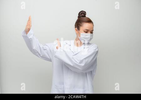 Junge schöne Ärztin im Mantel Angst und erschrocken vor Angst Ausdruck Stop Geste mit den Händen, schreiend in Schock. Stockfoto