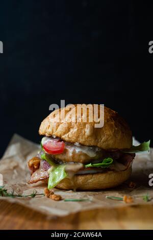 Frischer leckerer Burger auf schwarzem Hintergrund. Köstlicher frischer hausgemachter Burger auf einem Holztisch Stockfoto