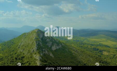 Schöne hohe Berge mit Grüns bedeckt und unter dem schimmernden wolkiger Himmel Stockfoto