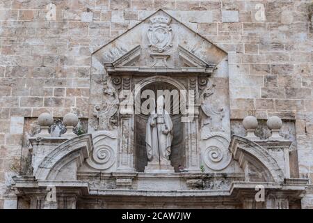 Gotisches Flachrelief auf der Kirche mit einer Statue von Priester und Säulen in valencia Stockfoto