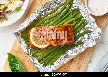 Folienverpackung Abendessen mit rotem Fisch. Lachsfilet mit Spargel. Im Ofen gebackenes warmes Abendessen Stockfoto