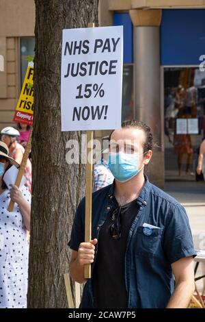 Oxford, Großbritannien. August 2020. NHS-Arbeiter und -Unterstützer nahmen an einer Kundgebung auf dem Bonner Platz in Oxford Teil, in der sie für Lohngerechtigkeit für alle NHS-Arbeiter aufriefen und protestierten, eine Lohnerhöhung zu fordern, um ihre Bemühungen während der covid Pandemie widerzuspiegeln.Dies war eine von etwa 38 ähnlichen Kundgebungen in ganz Großbritannien. Die Protestierenden behielten soziale Distanzierung aufrecht und trugen Masken. Während sie den Rednern zuhörten, hielten viele Plakate, die ihre Beschwerden und wie sie sich unterschätzt fühlten, hervorhoben. Abgebildet, Protestler hält NHS Pay Justice 15% Jetzt Plakat. Quelle: Stephen Bell/Alamy Stockfoto