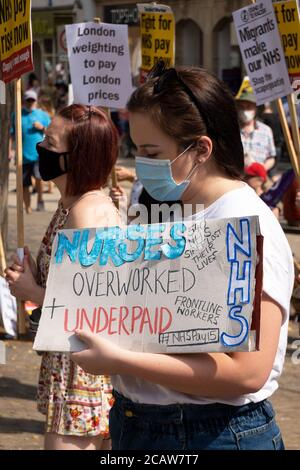 Oxford, Großbritannien. August 2020. NHS-Arbeiter und -Unterstützer nahmen an einer Kundgebung auf dem Bonner Platz in Oxford Teil, in der sie für Lohngerechtigkeit für alle NHS-Arbeiter aufriefen und protestierten, eine Lohnerhöhung zu fordern, um ihre Bemühungen während der covid Pandemie widerzuspiegeln.Dies war eine von etwa 38 ähnlichen Kundgebungen in ganz Großbritannien. Die Protestierenden behielten soziale Distanzierung aufrecht und trugen Masken. Während sie den Rednern zuhörten, hielten viele Plakate, die ihre Beschwerden und wie sie sich unterschätzt fühlten, hervorhoben. Im Bild, NHS Arbeiter mit Plakat - Krankenschwestern überarbeitet und unterbezahlt. Quelle: Stephen Bell/Alamy Stockfoto