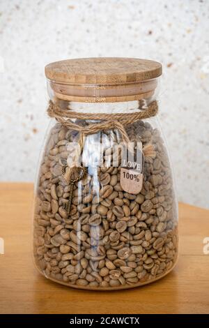 Grüne Kaffeebohnen im Glas auf einem Holztisch. Liebe Zeichen am Seil Stockfoto