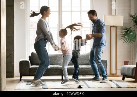 Positive energische junge Eltern tanzen mit kleinen Kindern. Stockfoto