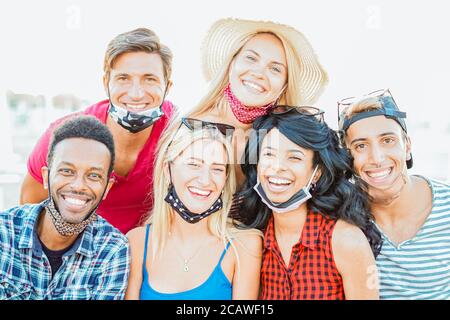 Gruppe von multirassischen Freunden, die ein Bild machen, während die Kamera fokussiert und mit Gesichtsmaske lächelt - Neues Lifestyle-Konzept Stockfoto