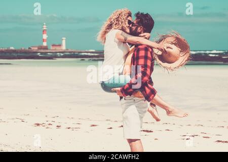 Nettes Paar von Menschen küssen einander mit Spaß und Genießen Sie zusammen am Strand auf dem Sand im Urlaub - zwei Erwachsene in der Liebe in den Ferien bei Sum Stockfoto