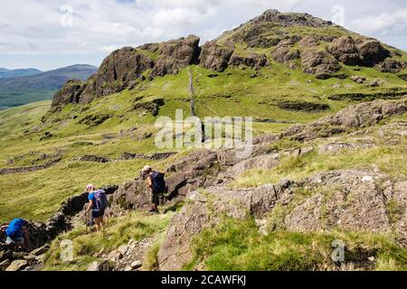 Wanderer wandern hinunter Moel Hebog zu Moel yr Ogof in den Bergen des Snowdonia National Park. Beddgelert, Gwynedd, Wales, Großbritannien Stockfoto