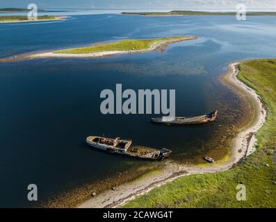 Luftaufnahme von verlassenen und verlassenen rostigen alten Schiffen in der Nähe von einsamen Insel im Arktischen Ozean. Russland. Weißes Meer Stockfoto