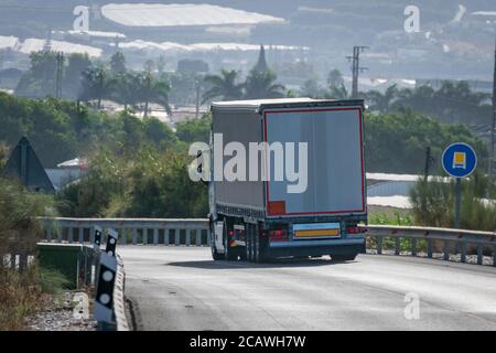 LKW mit einer Ladung gefährlicher Güter, die an einem Verkehrsschild vorbeifahren, das seinen Verkehr auf dieser Straße erlaubt. Stockfoto