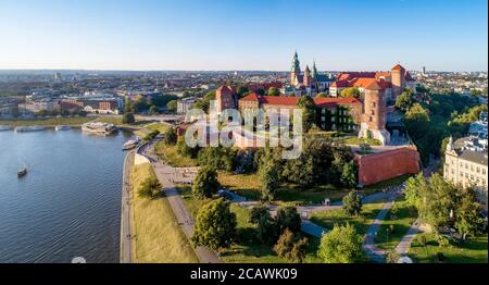 Krakau, Polen. Breites Luftpanorama bei Sonnenuntergang mit Royal Wawel Schloss und Kathedrale. Weichselufer, Touristenboote, Parks, Promenaden und Spazierwege Stockfoto