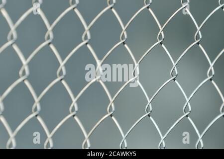 Silbriger Zaun aus Metallgeflecht der Platte, auf grauem fuzzy Hintergrund. Nahaufnahme Stockfoto