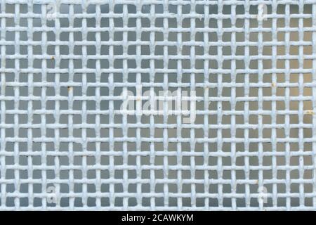 Hellblauer rostiger Zaun aus Metallgeflecht, quadratische Zellen, auf einem verschwommenen Hintergrund. Nahaufnahme. Vorderansicht Stockfoto