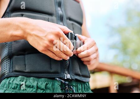 Hände des jungen Sportlers Befestigung Sicherheitsgurt auf der Taille Schwarze Sportjacke Stockfoto