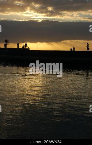 Silouhette von Leuten, die auf einem Pier auf Runion Island spazieren Stockfoto