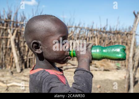 Junger Karamojong-Junge, der in einem ländlichen Dorf im Moroto District in Uganda Bier trinkt Stockfoto