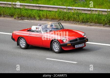 1974 Red MG B British Sports car; Vehicular Traffic Moving Vehicles, Cars Driving Vehicle auf britischen Straßen, Motoren, Autofahren auf der Autobahn M6-Netz. Stockfoto