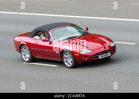 1997 90s Neunzigs Red Jaguar XK8 Convertible Auto; Fahrzeuge mit beweglichem Verkehr, Fahrzeuge, die Fahrzeuge auf britischen Straßen fahren, 90s Motoren, die auf dem Autobahnnetz der Autobahn M6 fahren. Stockfoto