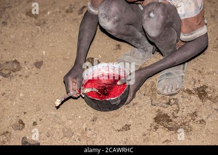 Reinigung von frischem Blut von Gerinnseln in einer Karamojong-Siedlung bei Nacht, Moroto District, Uganda Stockfoto