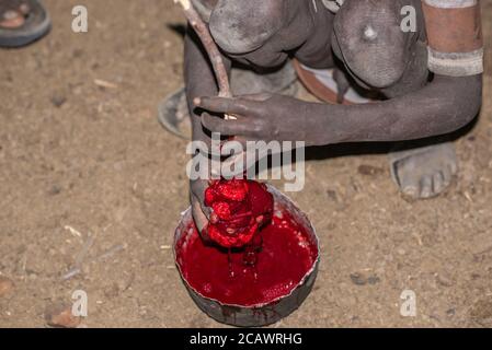 Reinigung von frischem Blut von Gerinnseln in einer Karamojong-Siedlung bei Nacht, Moroto District, Uganda Stockfoto