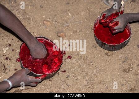 Reinigung von frischem Blut von Gerinnseln in einer Karamojong-Siedlung bei Nacht, Moroto District, Uganda Stockfoto