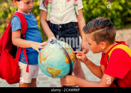 Zurück zur Schule. Schüler, die den Globus im Freien betrachten. Geografie- und Bildungskonzept Stockfoto