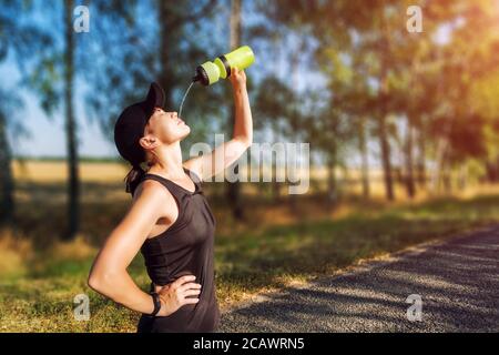 Stillende junge Frau, die Wasser aus der Flasche auf ihr Gesicht gießt Nach hartem Training Stockfoto