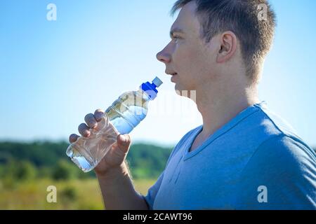 Sportlicher Kerl mit Gläsern trinkt Wasser aus der Flasche während Morgens Joggen und Sport Stockfoto