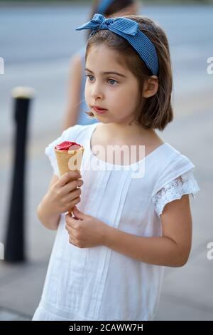 Nettes Mädchen zu Fuß durch die Stadt und essen Eis Stockfoto