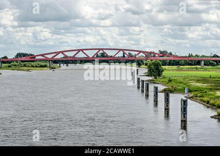 Zwolle, Niederlande, 21. Juli 2020: Blick über die IJssel zum roten Bogen der Hanzeboog-Eisenbahnbrücke Stockfoto