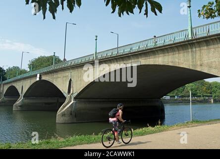 Eine Radfahrerin fährt neben der themse in richmond, surrey, england, und nähert sich der twickenham Brücke Stockfoto