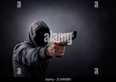 Mit Kapuze Mann mit einer Pistole in der Dunkelheit Stockfoto