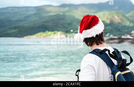 Mann im roten Hut des Weihnachtsmannes und Sonnenbrille am tropischen Strand. Neujahrs- oder Weihnachtsurlaubskonzept Stockfoto