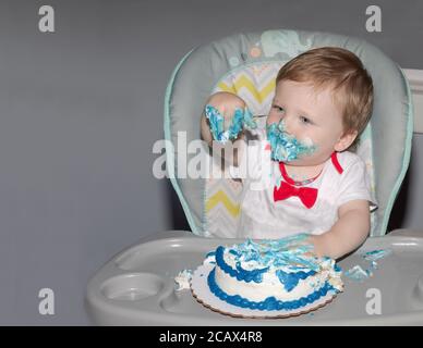 Kleinkind feiert seinen ersten Geburtstag mit zerschlackendem Kuchen. Stockfoto