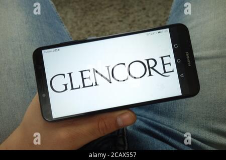 Mann hält Smartphone mit Glencore plc Firmenlogo Stockfoto