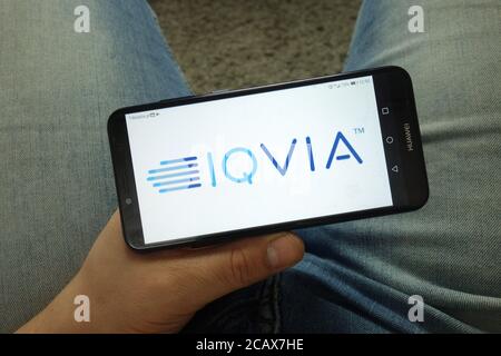 Mann hält Smartphone mit IQVIA Firmenlogo Stockfoto