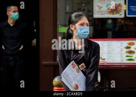 Das Personal im chinesischen Restaurant mit chirurgischen Gesichtsmasken erwartet die Gäste. Gerrard Street, Soho, London. Stockfoto