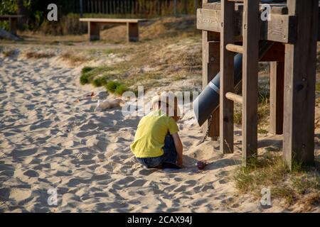 Ein kleiner Junge spielt in einem Sandkasten in einem Park Im Sommer mit Klettergerüst in Schuss Stockfoto