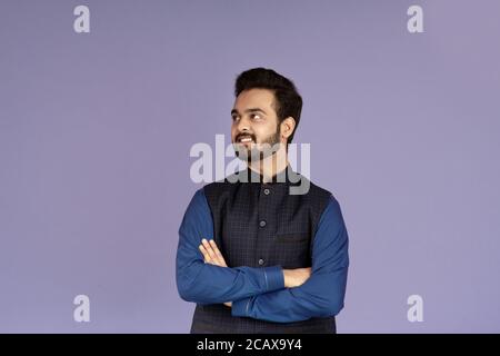 Positiver indischer Kerl stehend mit gekreuzten Armen auf lilac Hintergrund Stockfoto