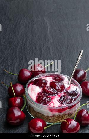 Hausgemachter Käsekuchen mit Kirschmarmelade im Glas Schwarzer Stein Hintergrund Stockfoto