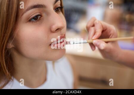 Professionelle Make-up-Künstler gilt Lippenstift. Hand von Make-up-Meister, Malerei Lippen von jungen schönen Modell. Make-up in Prozess. Beauty-Salon Stockfoto