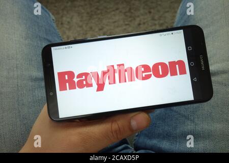 Mann hält Smartphone mit Raytheon Company Logo Stockfoto