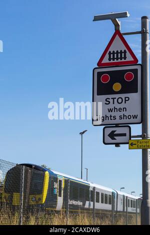 South Western Railway Zug nähert sich Wool Bahnhof mit Haltestelle, wenn die Lichter zeigen Zeichen für Bahnübergang in Wool, Dorset UK im August Stockfoto