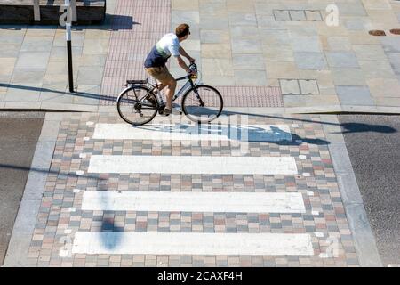 Ein männlicher Radfahrer auf einer Fußgängerüberfahrt, von oben gesehen, King's Cross, London, Großbritannien Stockfoto