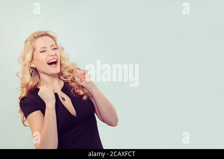 Moderne blonde Frau mit Fäusten in der Aufregung der Erfolg halten die Augen geschlossen Stockfoto