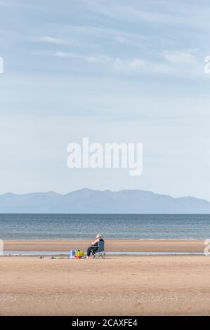 Barassie Beach, Troon, Schottland, Großbritannien. August 2020. Wetter in Großbritannien. Eine Frau am Barassie Beach mit der Isle of Arran am Horizont. Kredit: Skully/Alamy Live Nachrichten Stockfoto