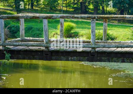 Holzbrücke über kleinen Fluss im Stadtpark Stockfoto